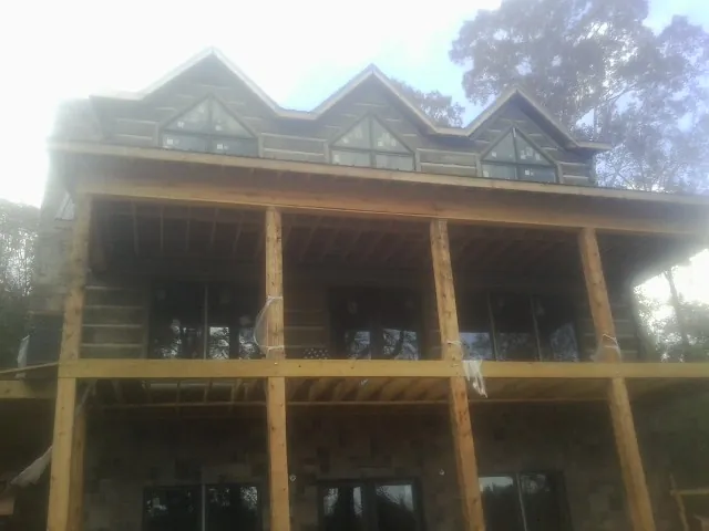Dormers and porch framing on a large log home under construction — Roof Coating work by our crew in Medical Lake