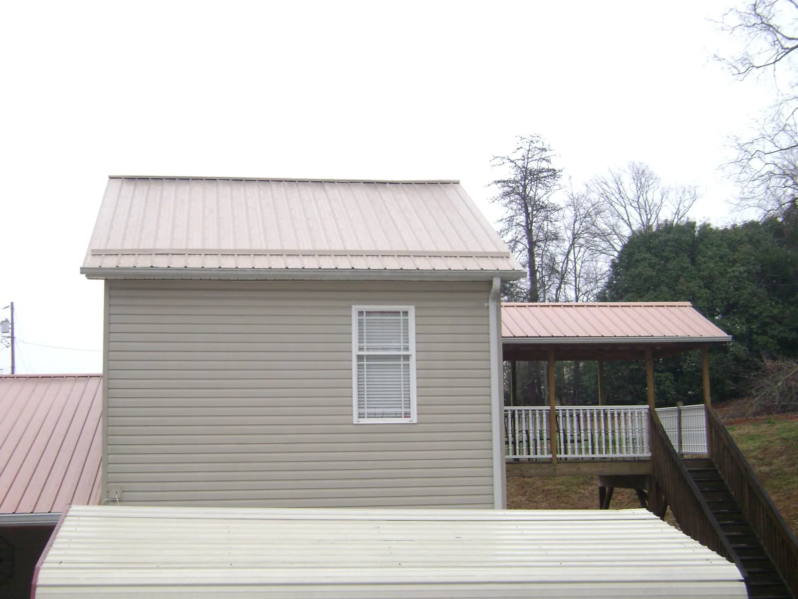 Tan metal roofs on a two story addition and attached porch, from a Roof Replacement job in Medical Lake