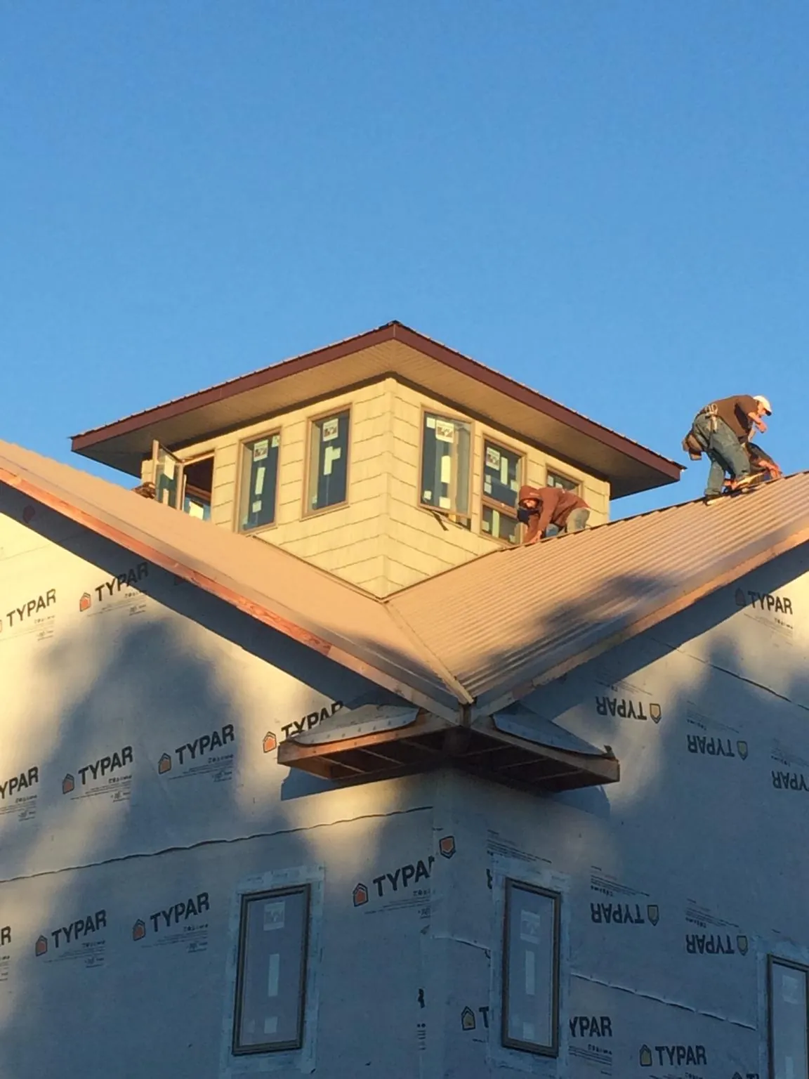 Roofers working around a rooftop cupola on a new metal roof at sunset — Roof Waterproofing in Medical Lake by Roofing Brothers